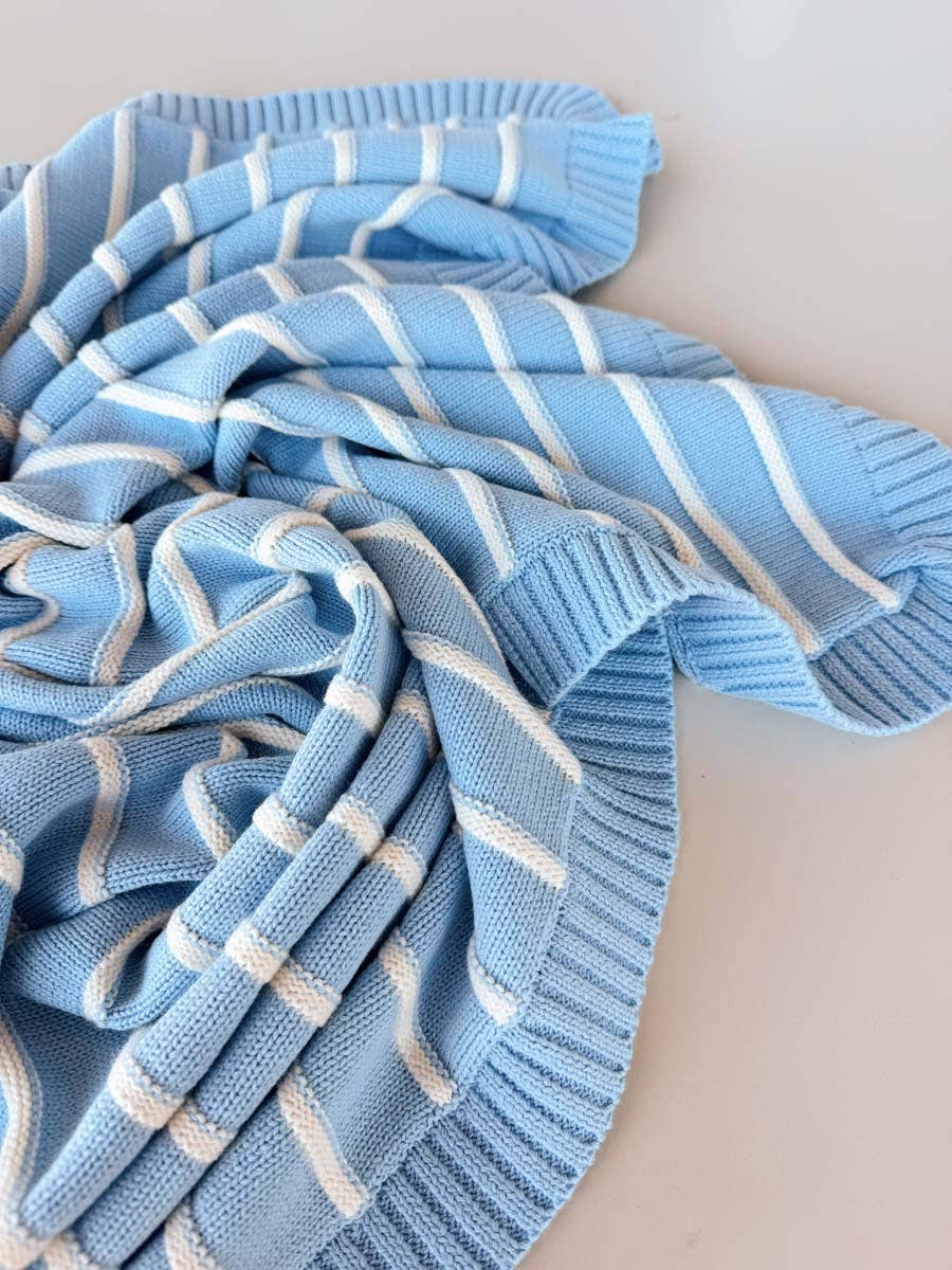 Blue and white striped knitted blanket on a light background