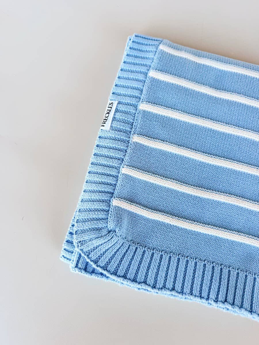 Blue and white striped blanket with a brand label on a light background